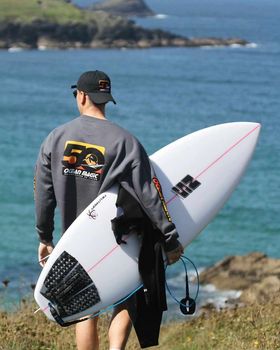 surfer walking to Newquay beach with ns surfboard