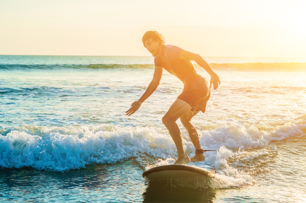 beginner surfer on softtop surfing a wave in the sunset