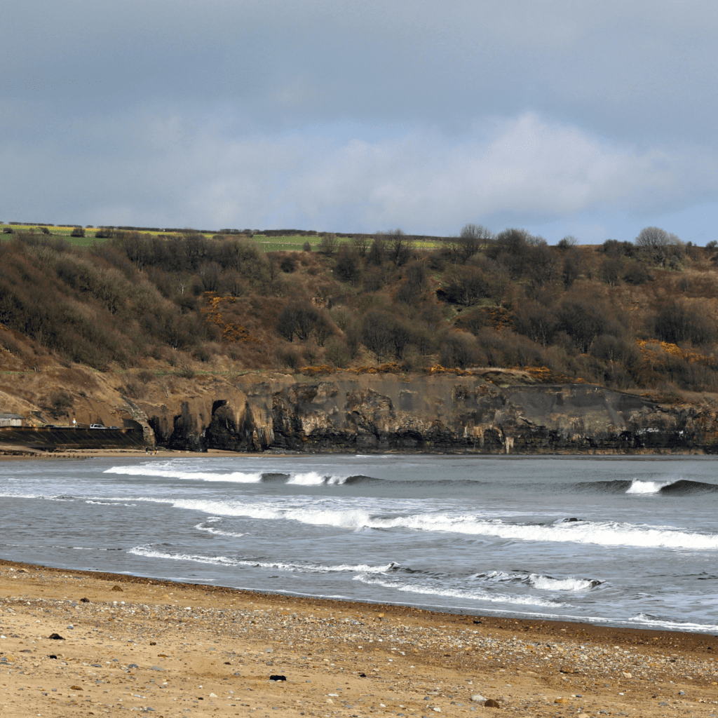 small waves on Whitby beach on a cloudy day