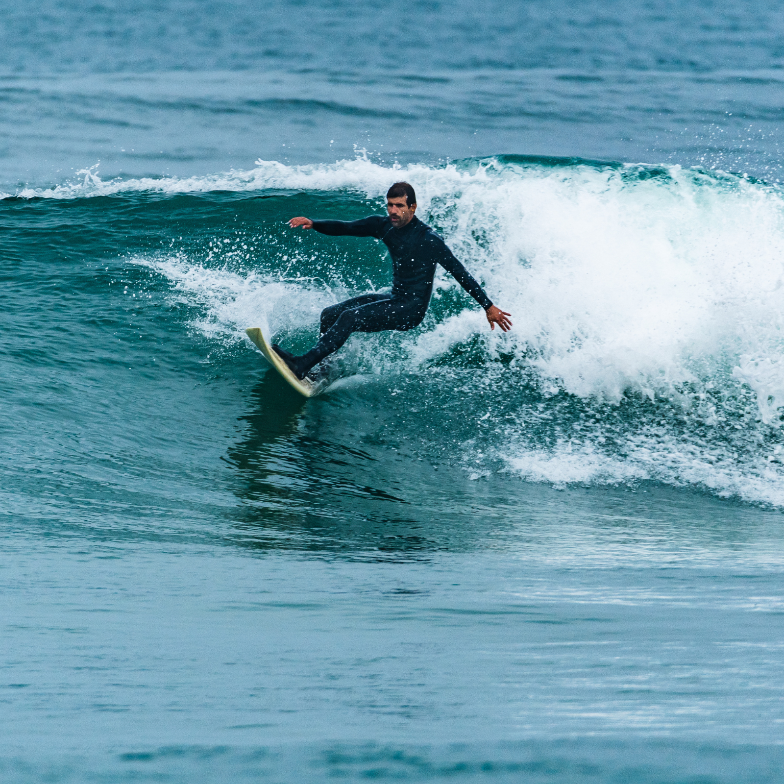 man surfing on a shortboard in a black wetsuit